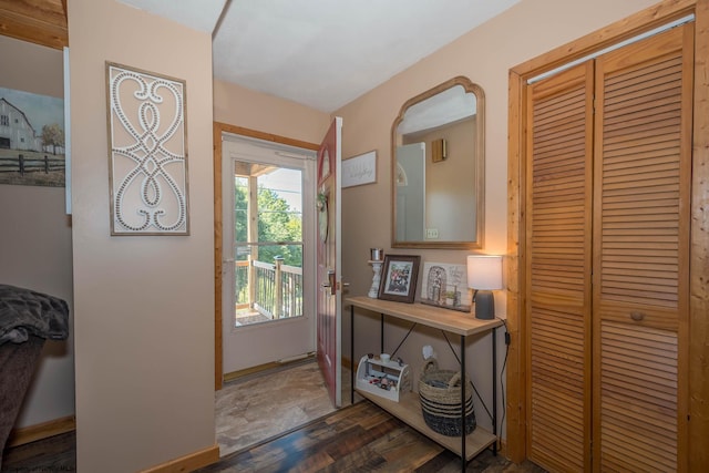 doorway featuring dark wood-style flooring and baseboards