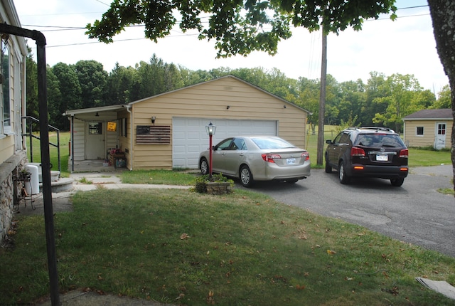 view of front of property featuring a garage, a front yard, and an outbuilding