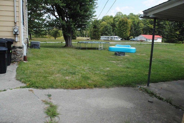 view of yard with a trampoline and central AC unit