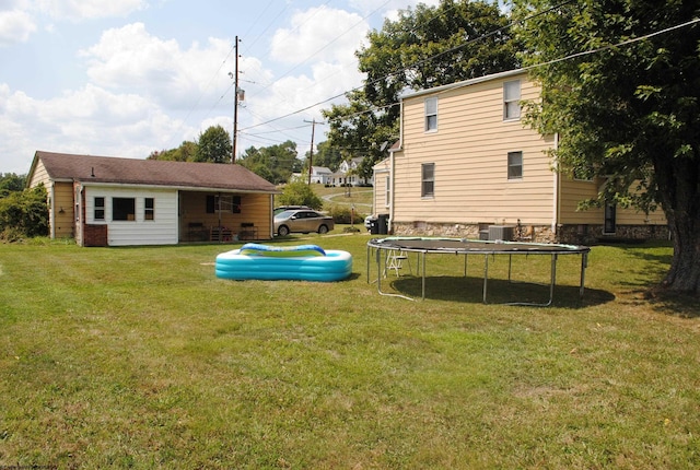 view of yard with a trampoline and central air condition unit