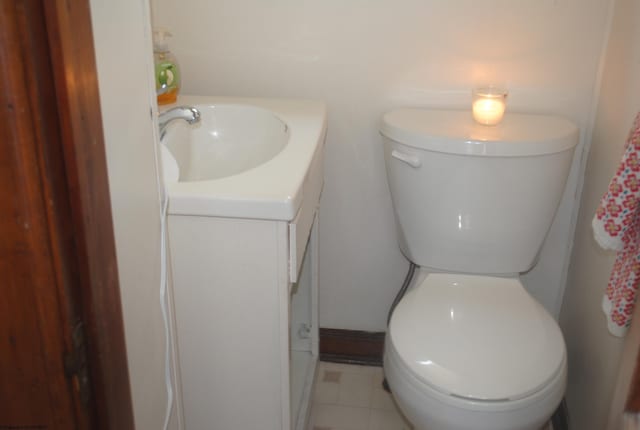 half bathroom with toilet, vanity, and tile patterned floors