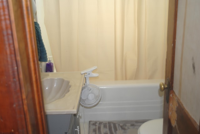 bathroom with toilet, shower / bath combo with shower curtain, and vanity