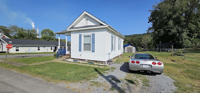 shotgun-style home featuring an outbuilding, a shed, a front yard, and a trampoline