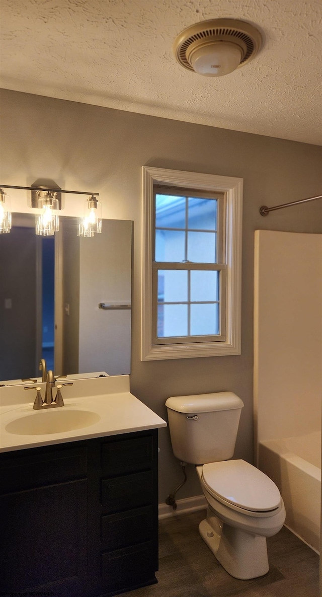 full bathroom featuring a textured ceiling, vanity, toilet, and bathtub / shower combination