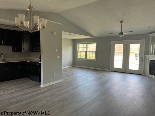 kitchen featuring light wood-type flooring, ceiling fan with notable chandelier, sink, and vaulted ceiling