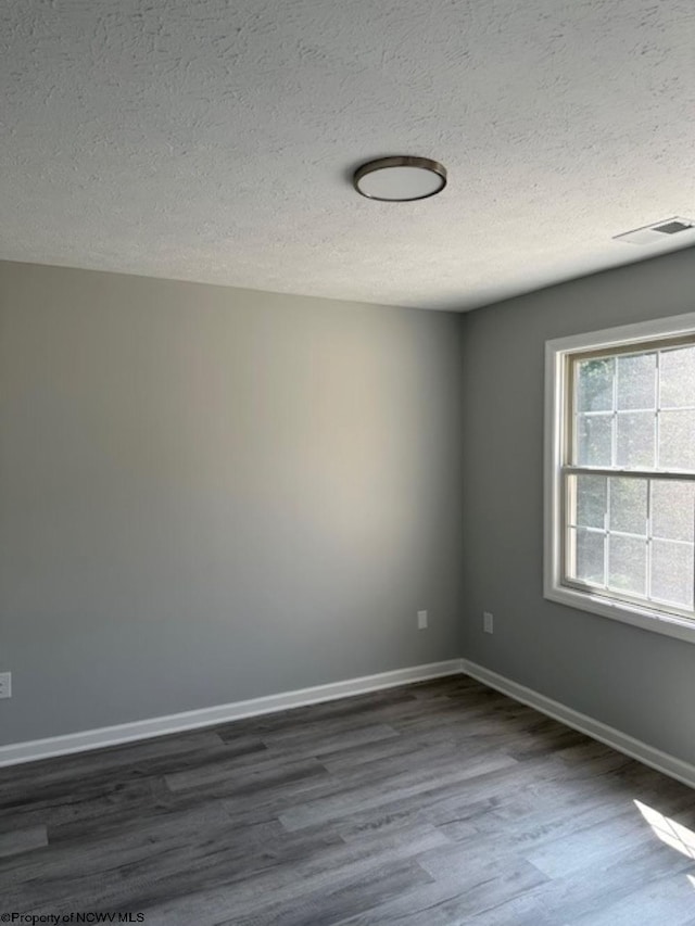 empty room featuring a textured ceiling and dark hardwood / wood-style flooring