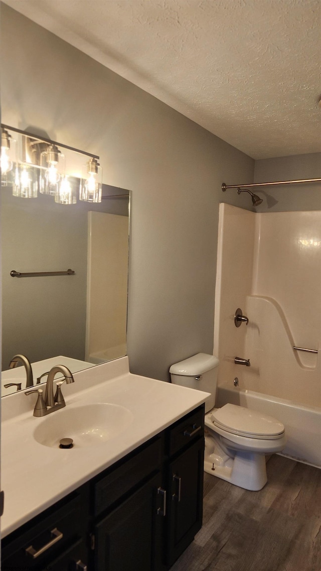 full bathroom featuring a textured ceiling, vanity, hardwood / wood-style floors, toilet, and bathtub / shower combination