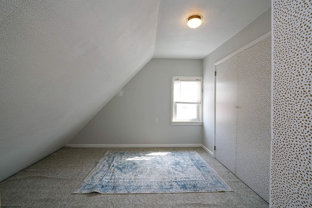 bonus room with vaulted ceiling, a textured ceiling, and light colored carpet