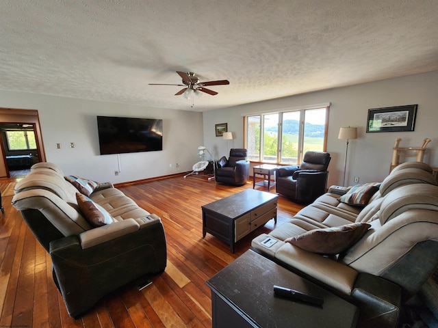 living room featuring ceiling fan, wood-type flooring, and a textured ceiling