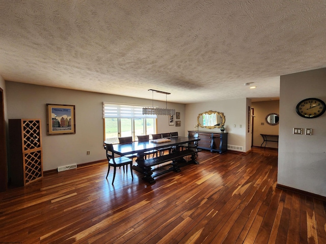 dining room with a textured ceiling and dark hardwood / wood-style flooring