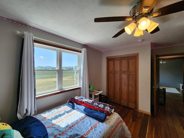 bedroom featuring dark hardwood / wood-style flooring, ceiling fan, a textured ceiling, and a closet