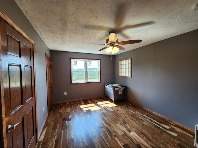 unfurnished bedroom with a textured ceiling, dark wood-type flooring, and ceiling fan