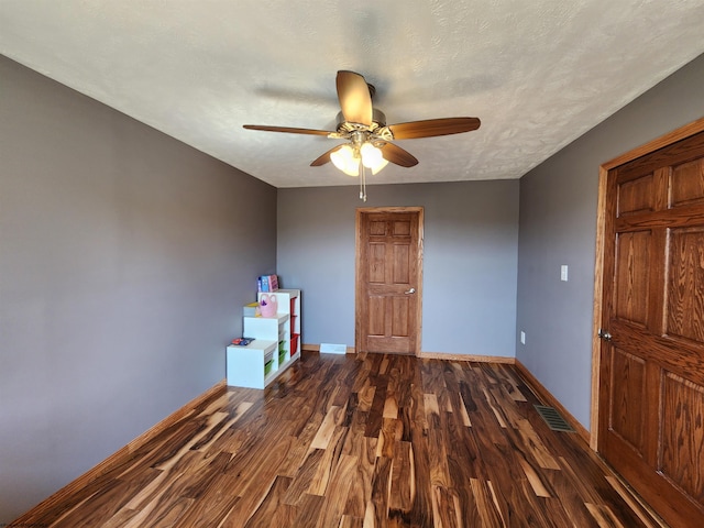 unfurnished bedroom with dark hardwood / wood-style flooring, ceiling fan, and a textured ceiling