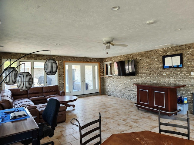 office featuring brick wall, french doors, a textured ceiling, and a wealth of natural light