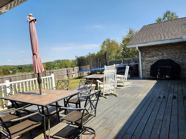 wooden deck featuring a trampoline and grilling area