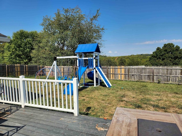 view of playground with a deck and a lawn