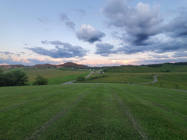 view of home's community with a rural view, a yard, and a mountain view