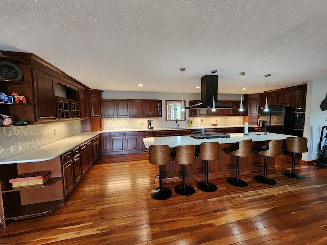 kitchen with a large island, dark hardwood / wood-style flooring, decorative light fixtures, island range hood, and a breakfast bar area