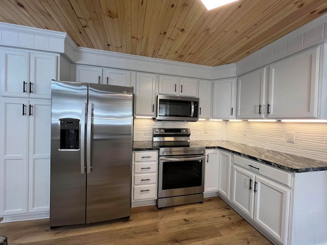 kitchen featuring wood ceiling, stainless steel appliances, dark stone counters, and white cabinets