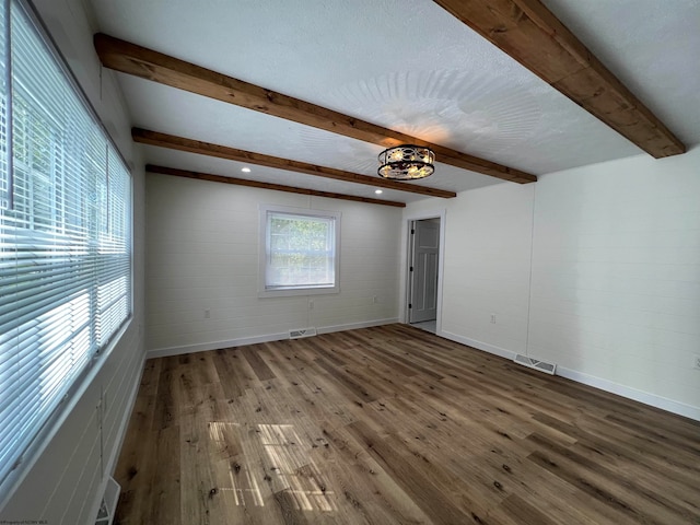 unfurnished room featuring hardwood / wood-style floors, beam ceiling, and a textured ceiling