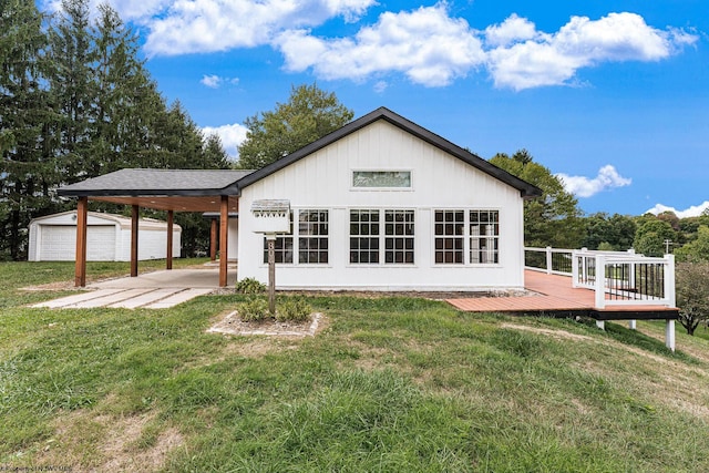 back of property with an outbuilding, a wooden deck, a yard, a carport, and a garage