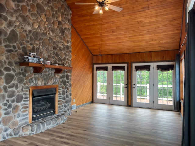 unfurnished living room featuring lofted ceiling, wood walls, ceiling fan, and a fireplace