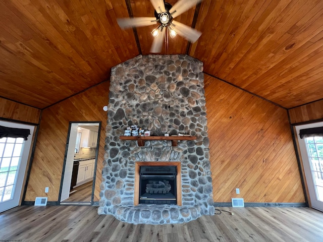 unfurnished living room featuring wood-type flooring, ceiling fan, vaulted ceiling, and a stone fireplace