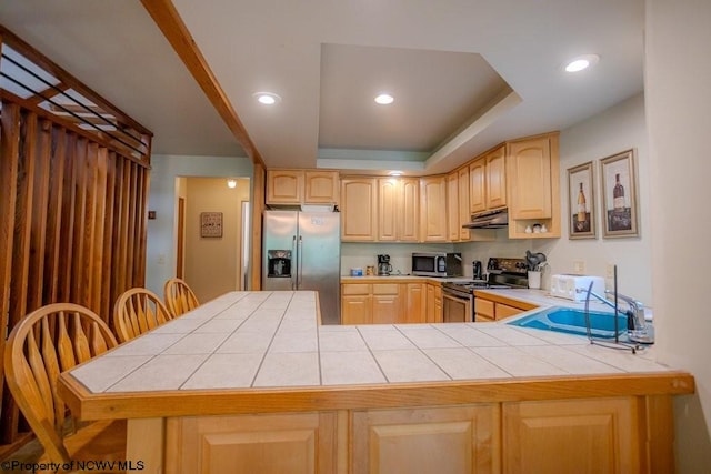 kitchen with tile countertops, stainless steel appliances, sink, light brown cabinets, and kitchen peninsula