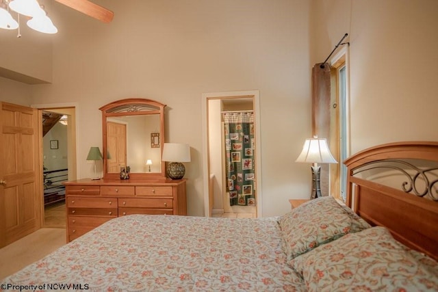 bedroom with ceiling fan, a towering ceiling, and light carpet