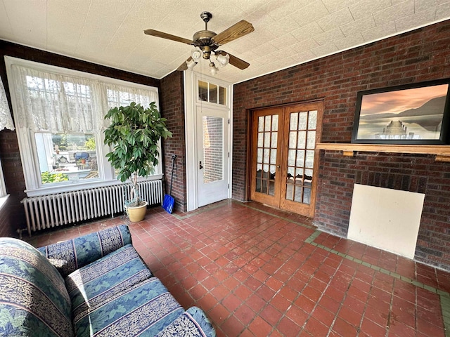 living room with brick wall, ceiling fan, radiator, and french doors