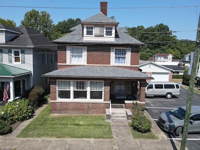 view of front of home with covered porch, a front yard, and a garage