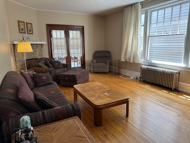 living room featuring plenty of natural light, radiator heating unit, light hardwood / wood-style flooring, and a fireplace