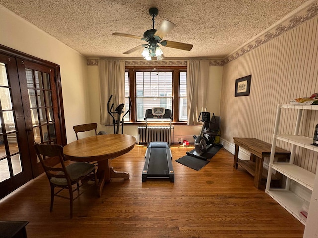 dining space featuring dark wood-type flooring, ceiling fan, radiator heating unit, and a textured ceiling