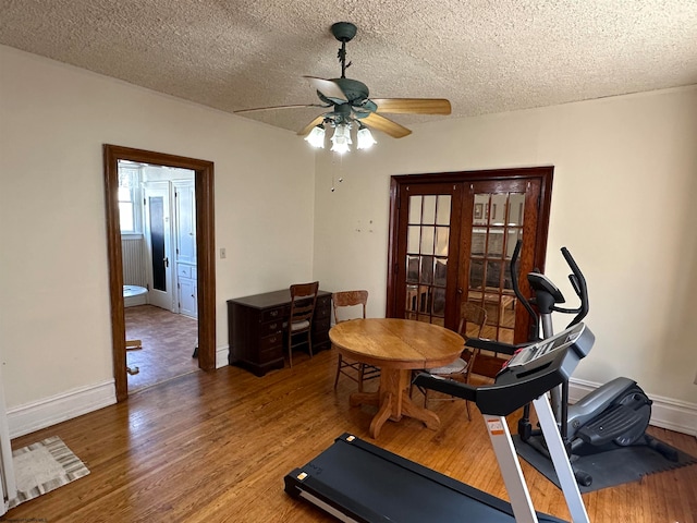 workout area with a textured ceiling, ceiling fan, and wood-type flooring