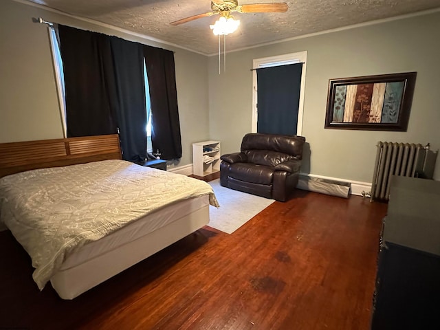 bedroom featuring dark hardwood / wood-style flooring, ceiling fan, radiator, and a textured ceiling