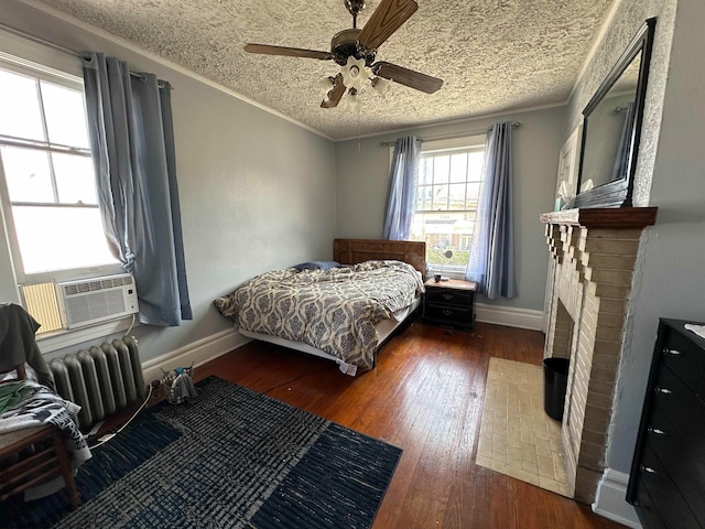 bedroom with a fireplace, dark wood-type flooring, ceiling fan, radiator heating unit, and ornamental molding