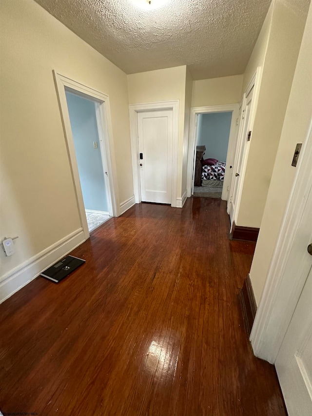 hallway with dark hardwood / wood-style flooring and a textured ceiling