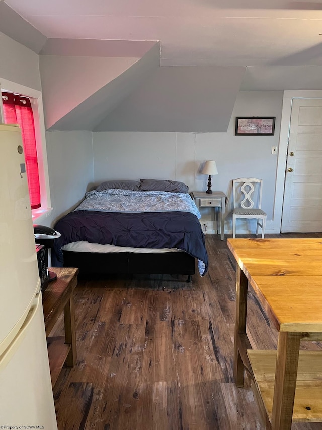 bedroom featuring lofted ceiling, white refrigerator, and dark hardwood / wood-style floors