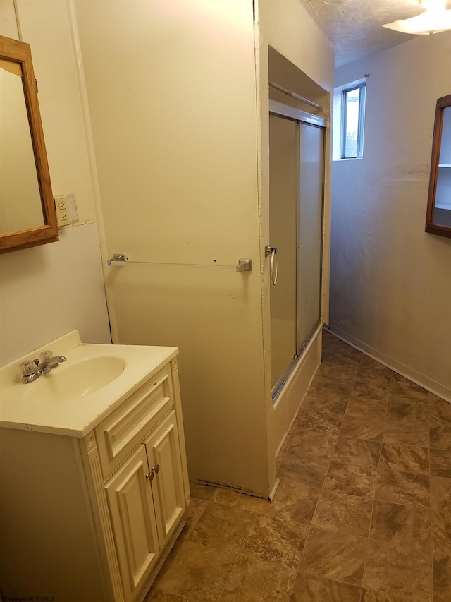 bathroom with a shower with door and vanity