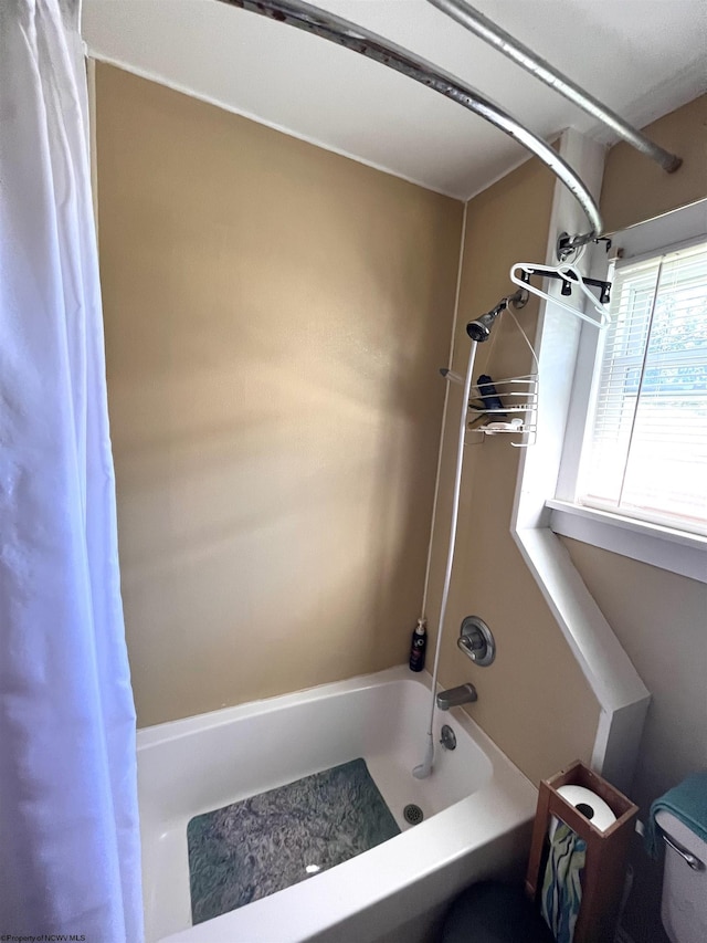 bathroom featuring toilet and shower / tub combo with curtain