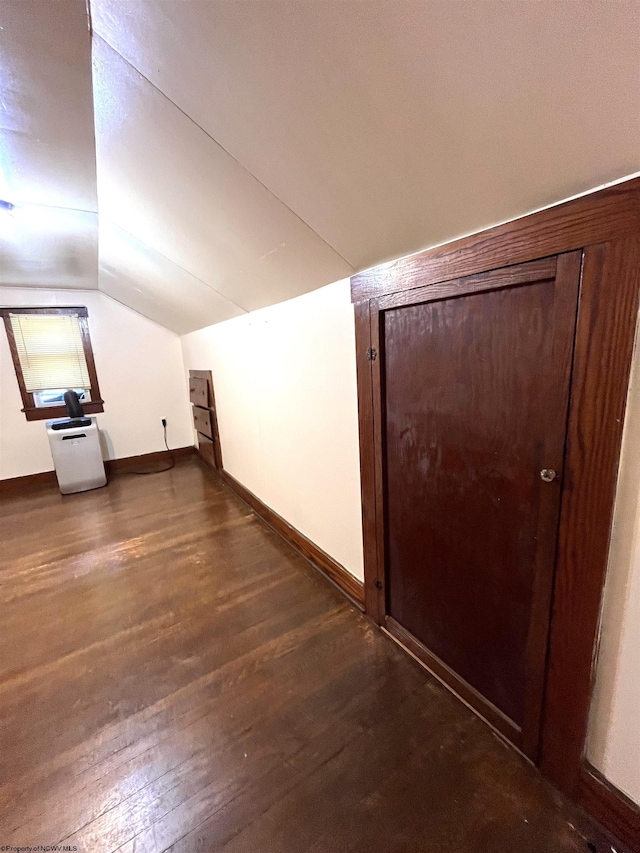 additional living space with lofted ceiling, dark wood-type flooring, and baseboards