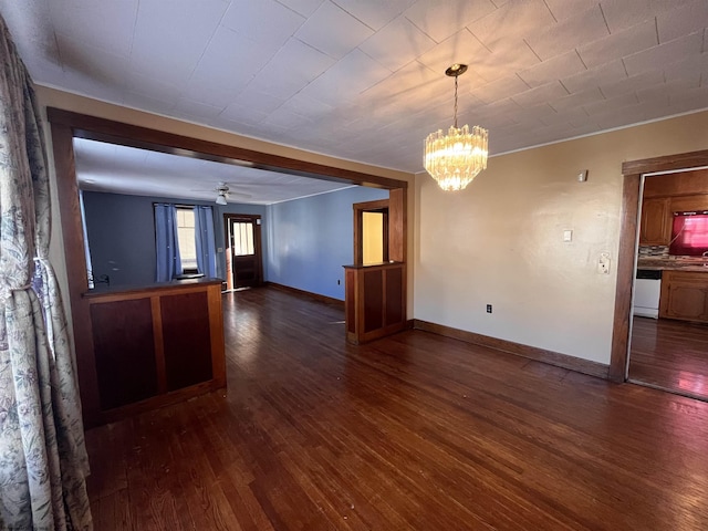 spare room with baseboards, dark wood finished floors, and ceiling fan with notable chandelier