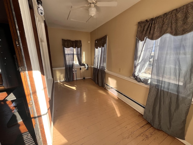 corridor featuring a baseboard radiator, attic access, and light wood-style flooring