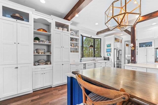 kitchen with dark hardwood / wood-style floors, beamed ceiling, stainless steel fridge, hanging light fixtures, and white cabinets