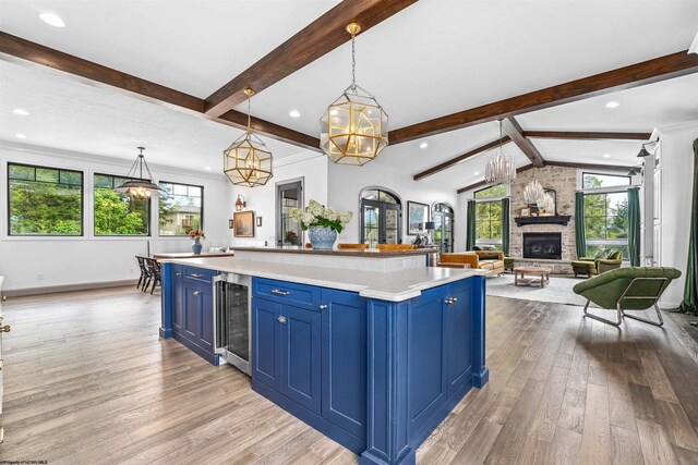 kitchen featuring blue cabinets, plenty of natural light, beverage cooler, and a fireplace