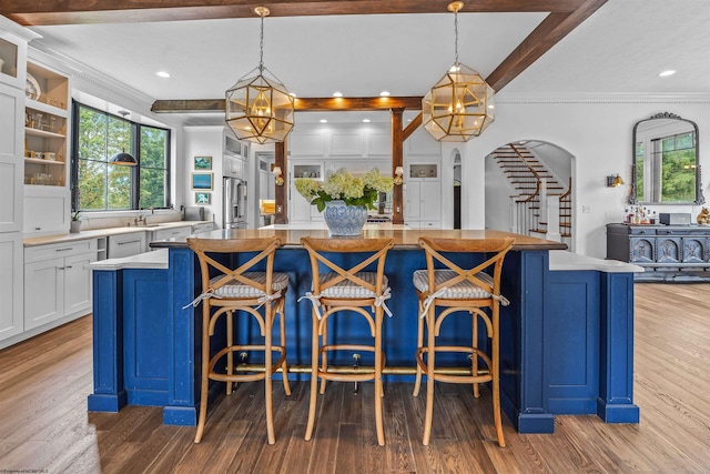 kitchen with light hardwood / wood-style floors, a kitchen island, white cabinets, and hanging light fixtures