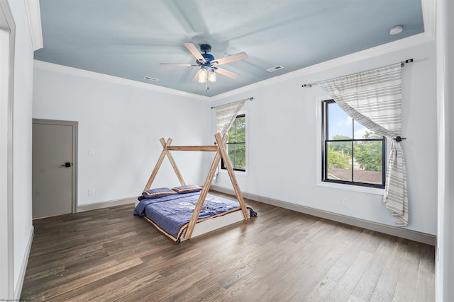 workout area featuring ceiling fan, plenty of natural light, dark hardwood / wood-style floors, and crown molding