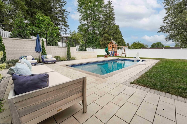 view of swimming pool featuring a lawn, a patio, and a playground