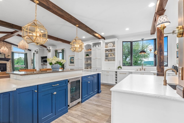 kitchen with plenty of natural light, a stone fireplace, beverage cooler, a kitchen island, and blue cabinets