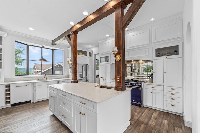 kitchen with appliances with stainless steel finishes, white cabinetry, an island with sink, and light stone countertops